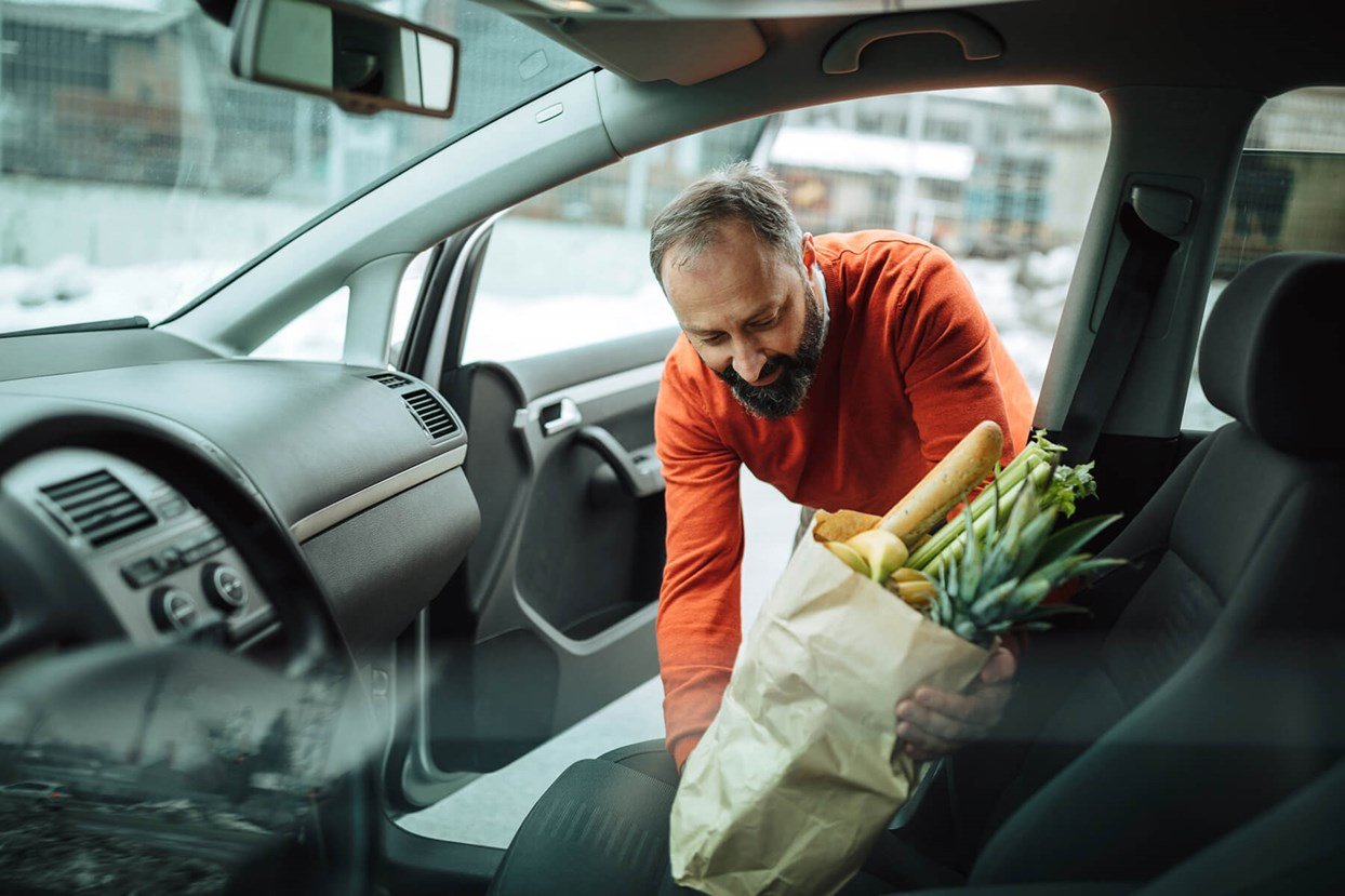Bild av man som packar in sina shoppingkassar i en bil. 