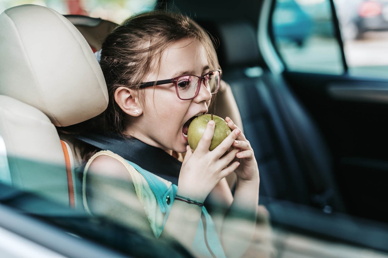 Bild av barn som äter äpple i en bil.